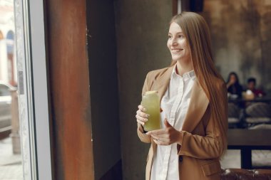 Bir kafede durup kokteyl içen zarif bir kadın.