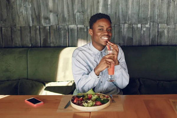 Uomo nero seduto in un caffè e mangiare un'insalata di verdure — Foto Stock