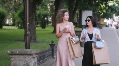 İki Avrupalı kadın alışveriş torbalarıyla sokaklarda geziniyor ve konuşuyorlar.