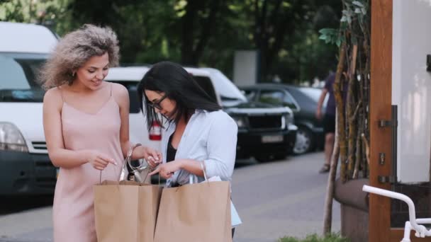 Två vackra kvinnor vänner med shoppingväskor i staden — Stockvideo