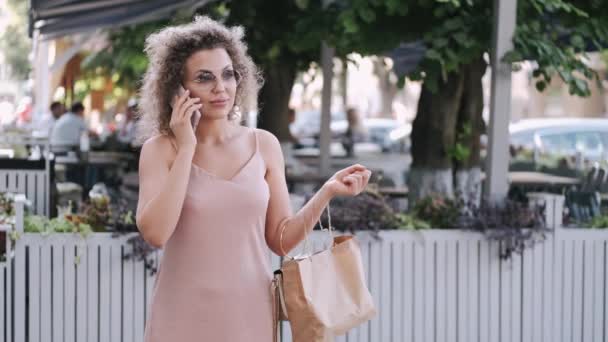 Kaunis nainen laukku matkamuistoja puhuu puhelimitse — kuvapankkivideo