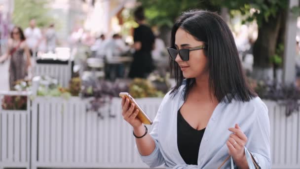 Aantrekkelijke vrouwen met een smartphone in de zomerstad — Stockvideo