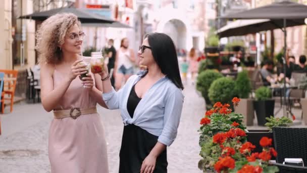 Feliz dos mujeres están bebiendo cócteles en la calle de verano — Vídeos de Stock