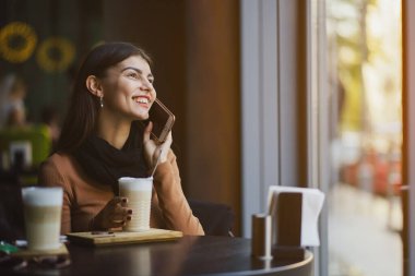 Esmer kız restoranda telefon kullanıyor.