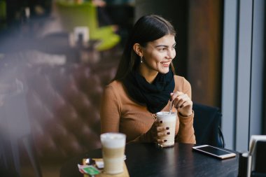 Esmer kız restoranda telefon kullanıyor.