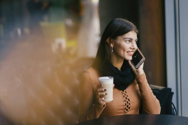 Esmer kız restoranda telefon kullanıyor.