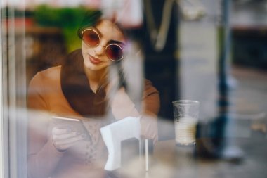 Esmer kız restoranda telefon kullanıyor.