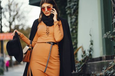 Şık bir kız telefonunu kullanarak şehirde dolaşıyor.