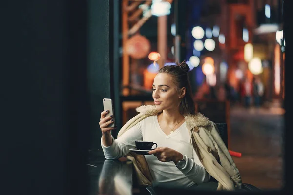 Lány ül a kávézó előtt használja a telefonját — Stock Fotó
