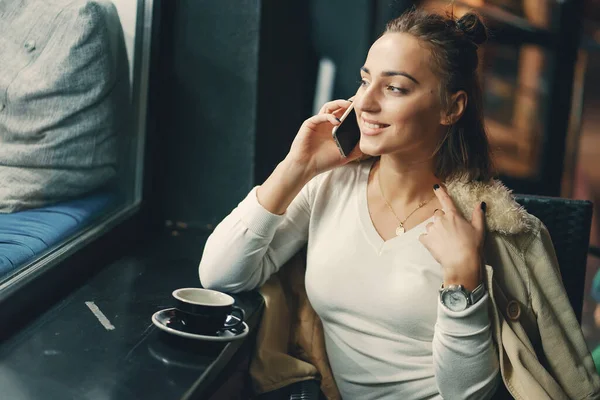 Fille assise à l'extérieur d'un café en utilisant son téléphone — Photo