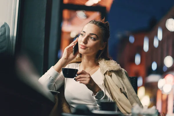 Fille assise à l'extérieur d'un café en utilisant son téléphone — Photo