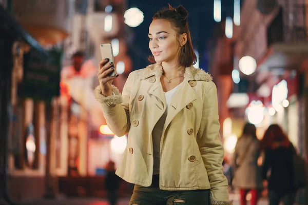 Dziewczyna sprawdza swój telefon na zewnątrz w nocy — Zdjęcie stockowe