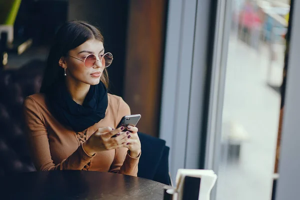Брюнетка дівчина використовує телефон, перебуваючи в ресторані — стокове фото