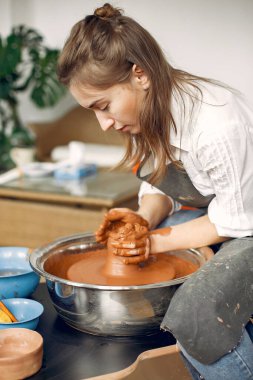 Çömlek makinesinde kilden vazo yapan bir kız.
