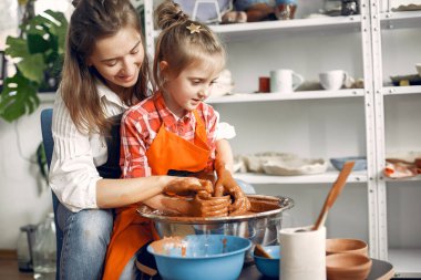 İnsanlar çömlek makinesinde kilden vazo yapıyorlar.