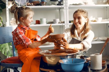 İnsanlar çömlek makinesinde kilden vazo yapıyorlar.