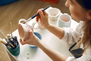 Çanak çömlekte tabak boyayan genç bir kadın.