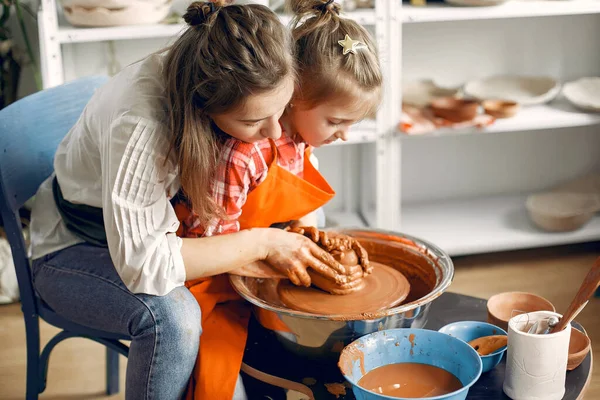 İnsanlar çömlek makinesinde kilden vazo yapıyorlar.