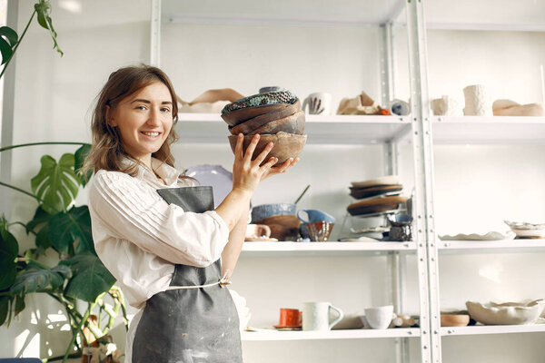 A young woman holds a ceramics dish in her hands