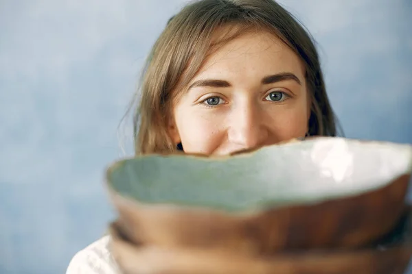 Een jonge vrouw houdt een keramiek schaaltje in haar handen — Stockfoto