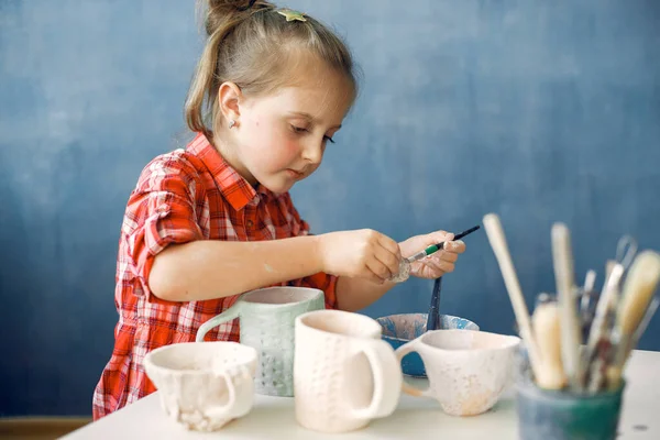 Een klein meisje schilderen afwas in een aardewerk — Stockfoto