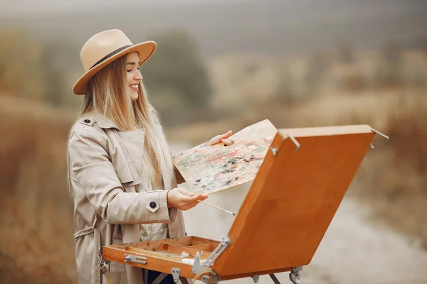 Donna in una pittura cappotto marrone in un campo — Foto Stock