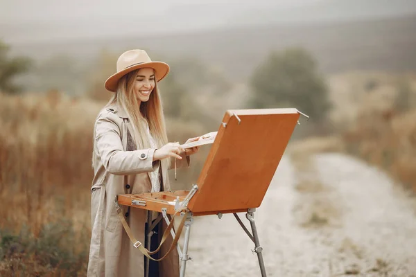 Donna in una pittura cappotto marrone in un campo — Foto Stock