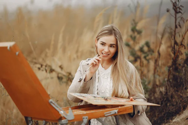 Donna in una pittura cappotto marrone in un campo — Foto Stock