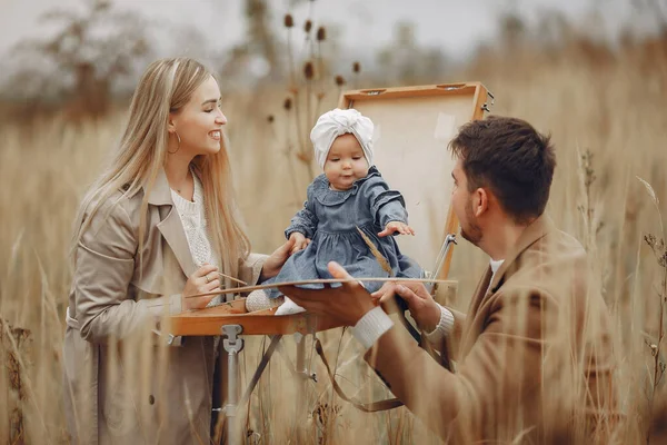 Família com pequena filha pintando em um campo de outono — Fotografia de Stock