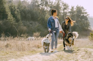 Bir bahar tarlasında köpekli iki şık kız.