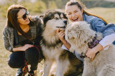 Bir bahar tarlasında köpekli iki şık kız.