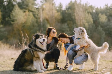 Bir bahar tarlasında köpekli iki şık kız.