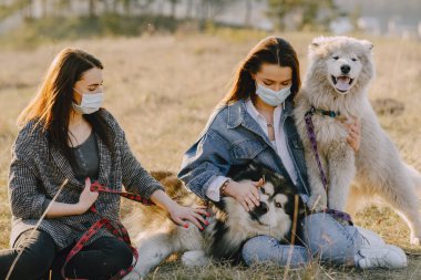 Bir bahar tarlasında köpekli iki şık kız.
