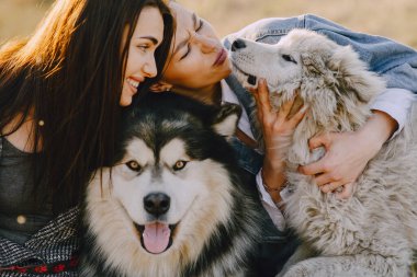 Bir bahar tarlasında köpekli iki şık kız.