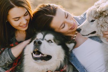 Bir bahar tarlasında köpekli iki şık kız.