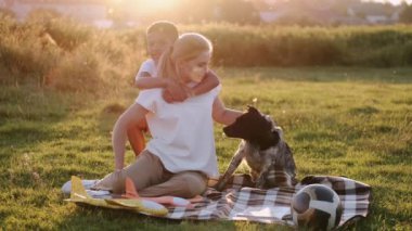 Anne ve oğlu köpekleriyle parkta dinleniyorlar.
