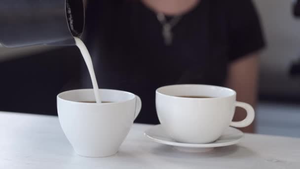 Бариста наливает молоко в чашку кофе — стоковое видео