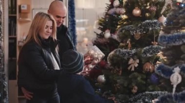 Anne ve baba Noel süslerini küçük oğluyla birlikte alıyorlar.