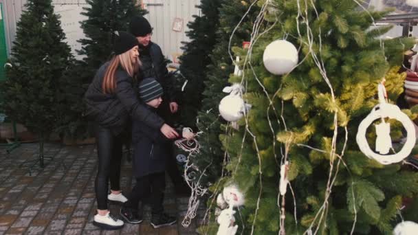 Γονείς με το παιδί επιλέγουν Christmas δέντρο μαζί στην αγορά — Αρχείο Βίντεο