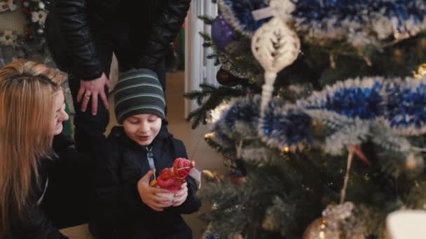 Anne ve baba Noel süslerini küçük oğluyla birlikte alıyorlar. — Stok video