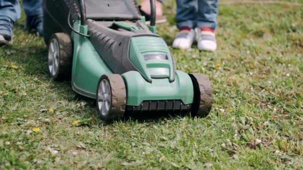 Cropped view of lawn-mover and legs on grass in village — Stock Video