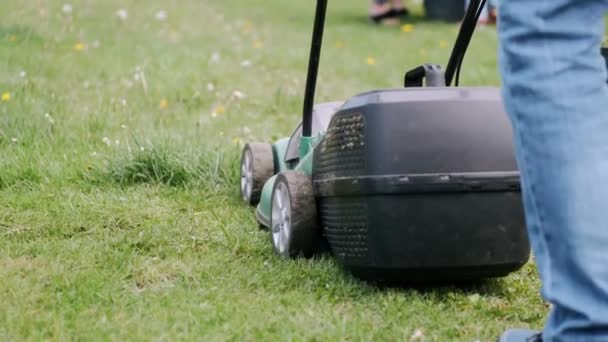 Cropped view of lawn-mover and legs on grass in village — Stock Video