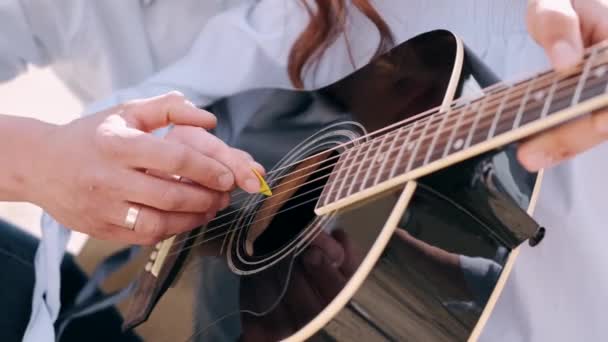 Парень крупным планом учит девушку играть песню — стоковое видео