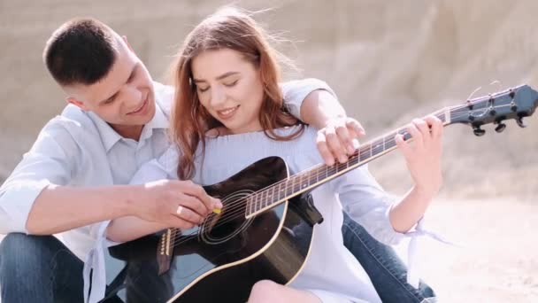 Парень учит девушку играть песню в карьере — стоковое видео