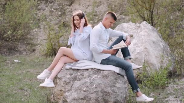 Pria dan wanita duduk di atas batu dan membaca buku bersama — Stok Video
