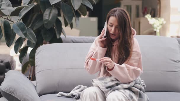 A senhora doente está falando por telefone com um termômetro nas mãos — Vídeo de Stock