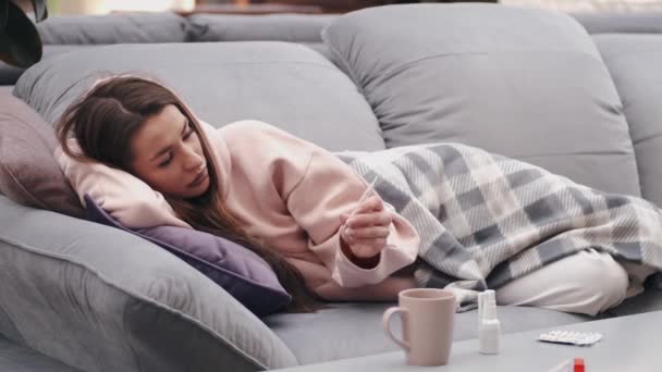 A mulher sentindo-se doente está deitada na cama e verificando a temperatura — Vídeo de Stock