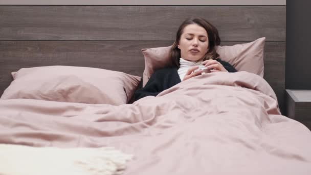 A mulher doente fica na cama e verifica a temperatura. — Vídeo de Stock