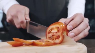 Tahta üzerinde sebze doğrayan bir kadının elleri.