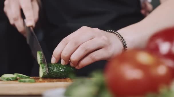 Hände einer Frau, die Gemüse auf einem Holzbrett hacken — Stockvideo